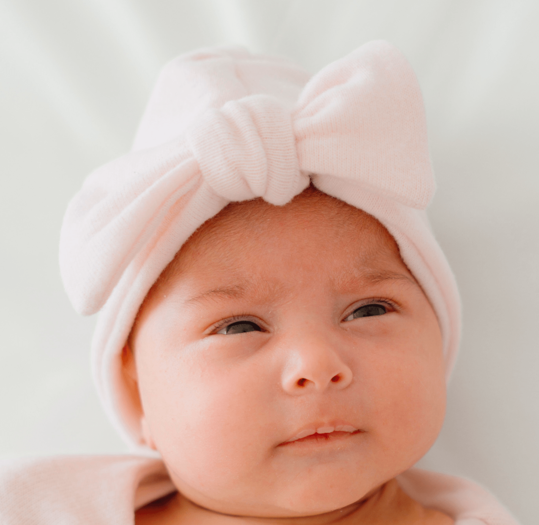 Newborn wearing Mama Coco bamboo baby beanie in plush pink cashmere design in plush dreams fabric.
