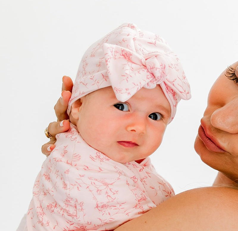 Reversible baby beanie with ruched bow in whimsical garden design.
