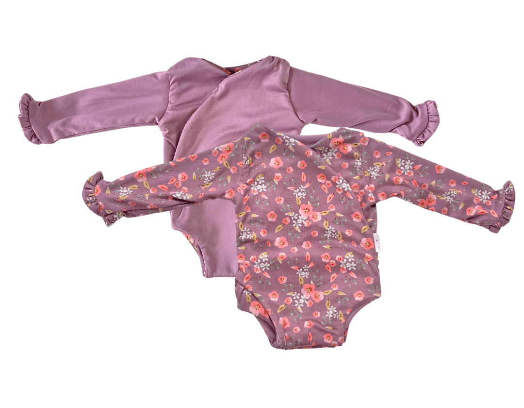 Reversible peachy lilac long sleeve ruffle cuff baby onesie.