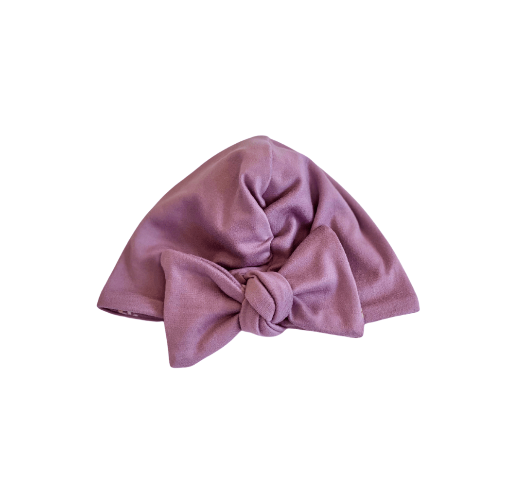 Reversible soft ruched baby beanie with bow made from classic brushed fabric in the Peachy Lilac design.