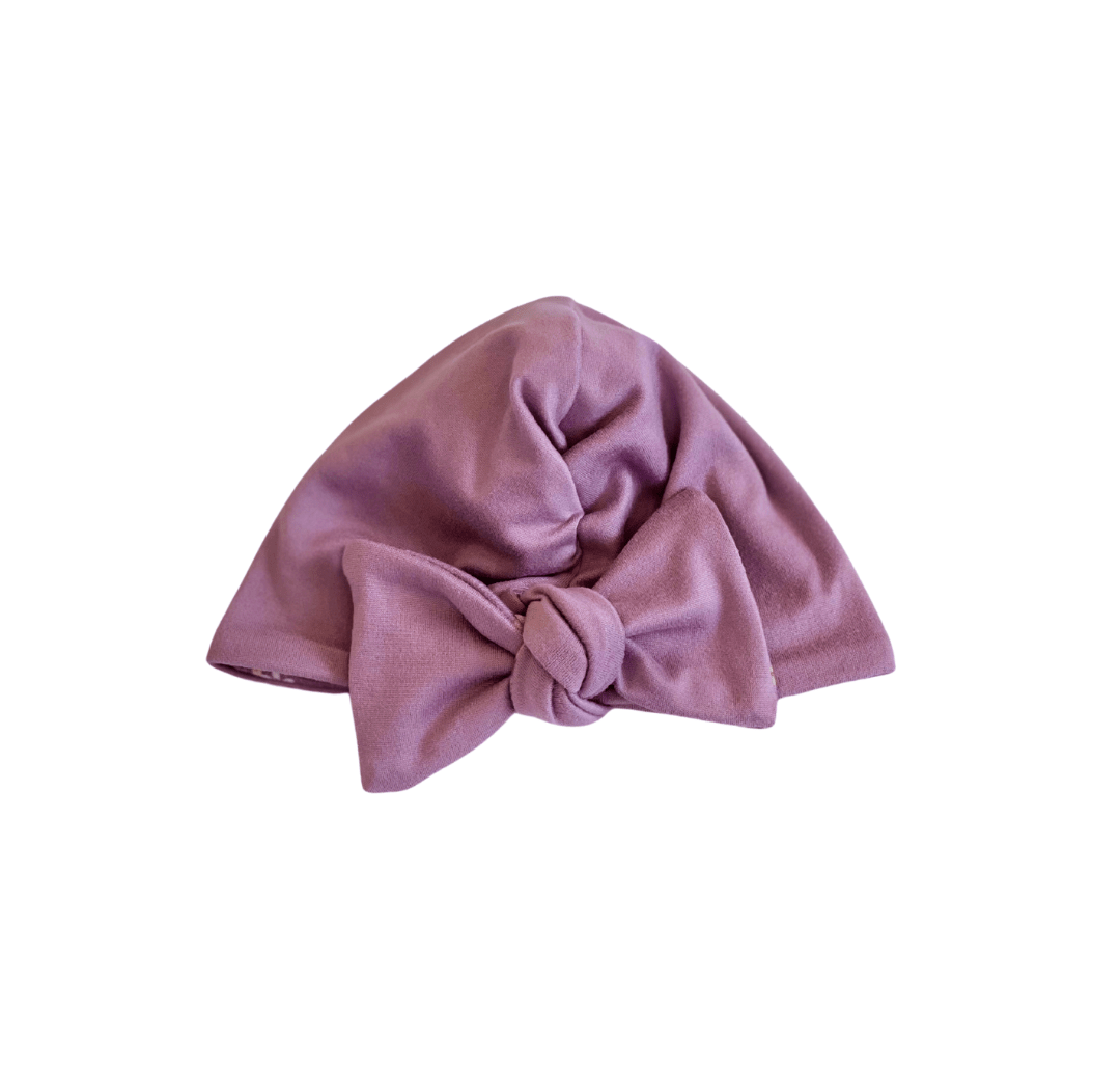 Reversible soft ruched baby beanie with bow made from classic brushed fabric in the Peachy Lilac design.