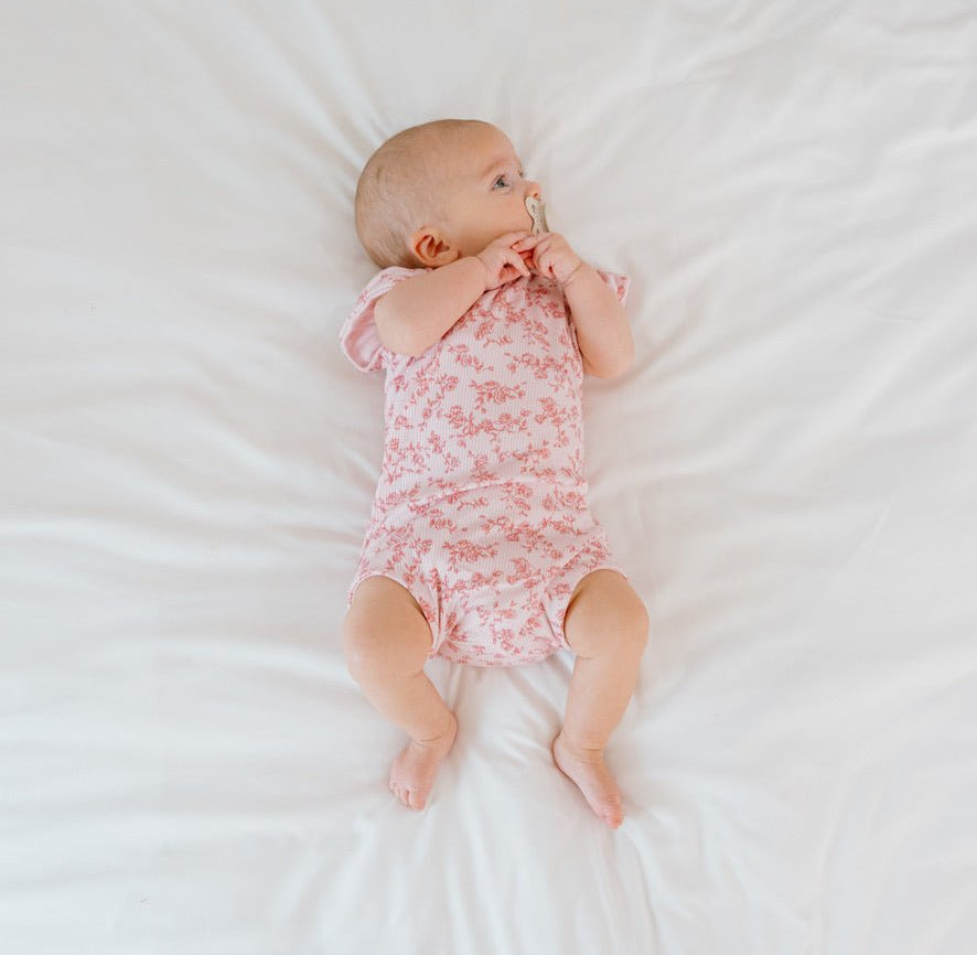 Baby flutter sleeve onesie made from silky modal fabric in bitty pink blooms design.