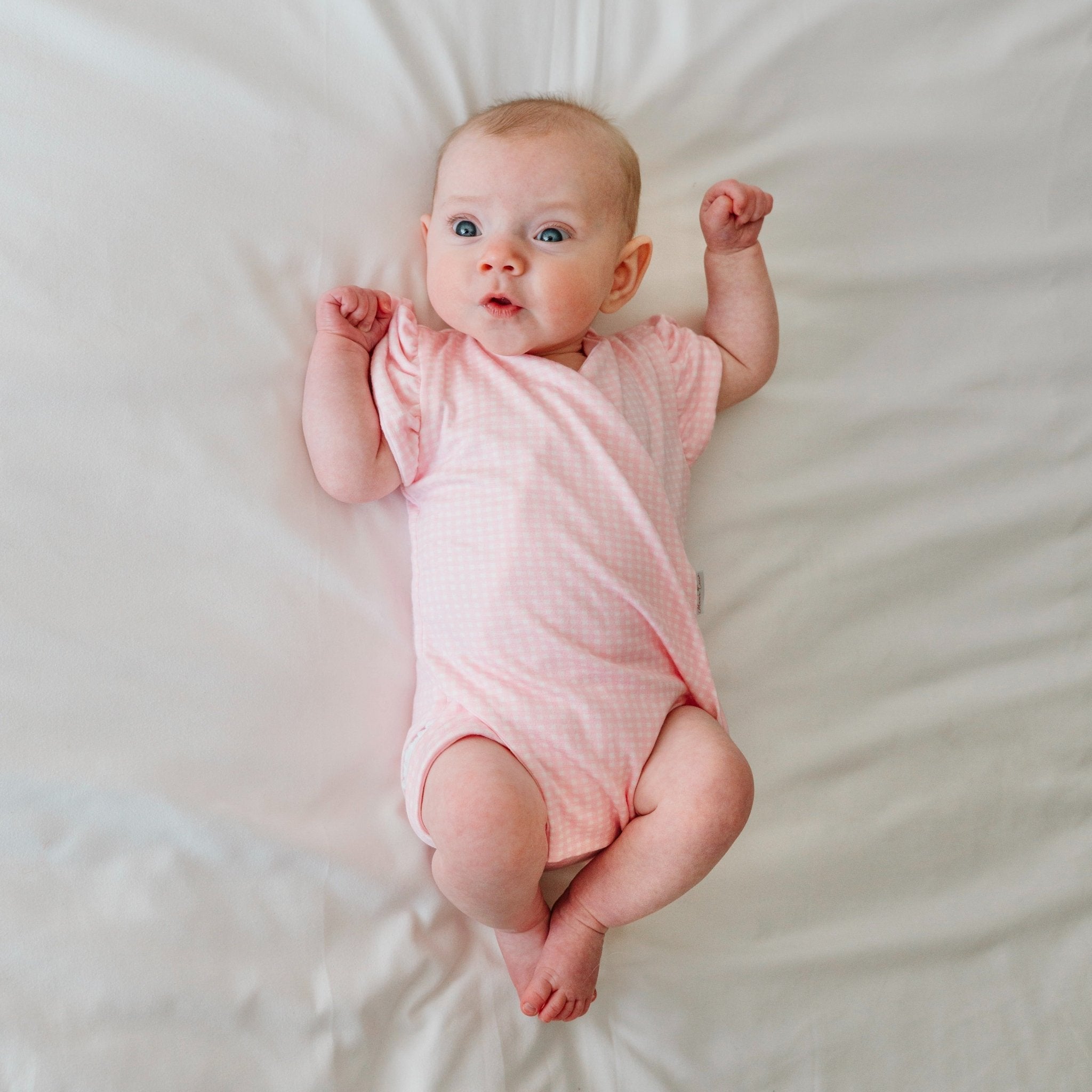 Baby flutter sleeve onesie made from silky modal fabric in baby pink gingham design.