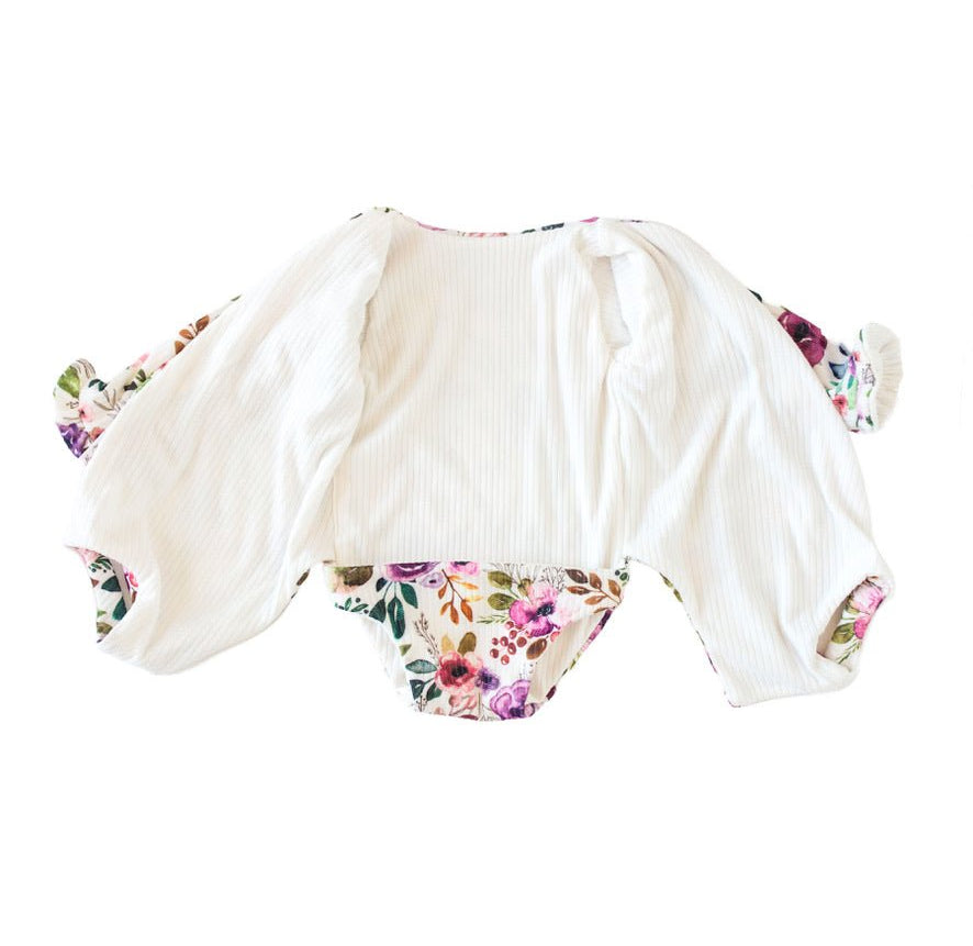 Long sleeve winged baby bodysuit featuring reversible ruffle cuffs in soft Ivory Wildflowers design brushed fabric.