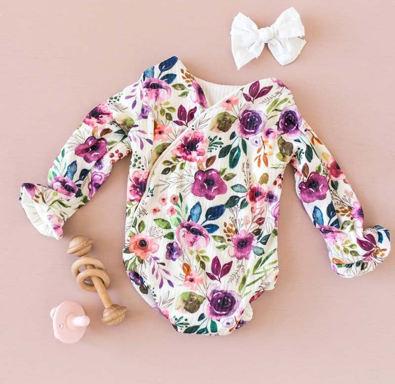 Long sleeve winged baby bodysuit featuring ruffle cuffs in soft Ivory Wildflowers design brushed fabric.