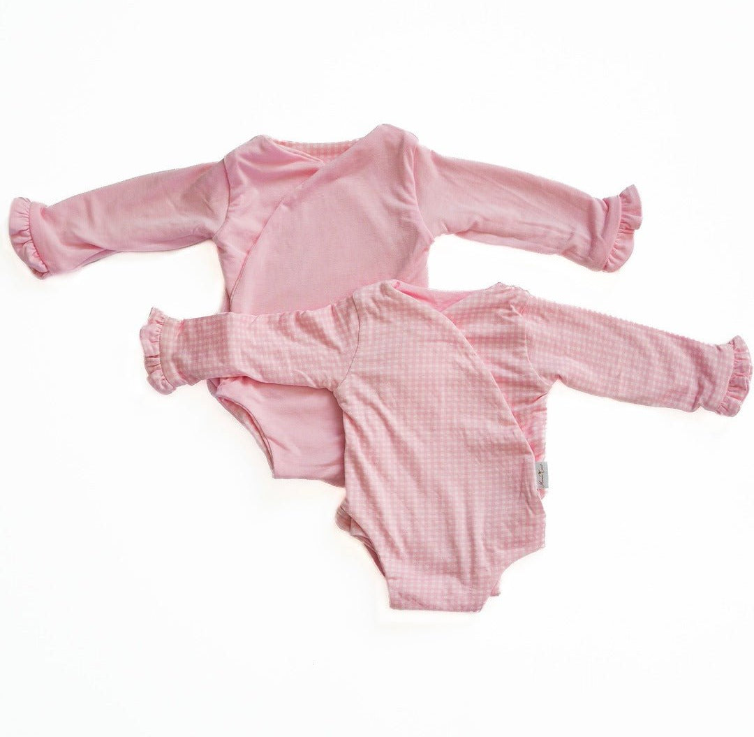 Reversible baby pink gingham long sleeve ruffle cuff onesie.