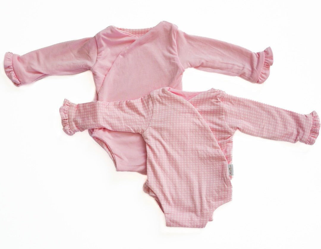 Reversible baby pink gingham long sleeve ruffle cuff onesie.
