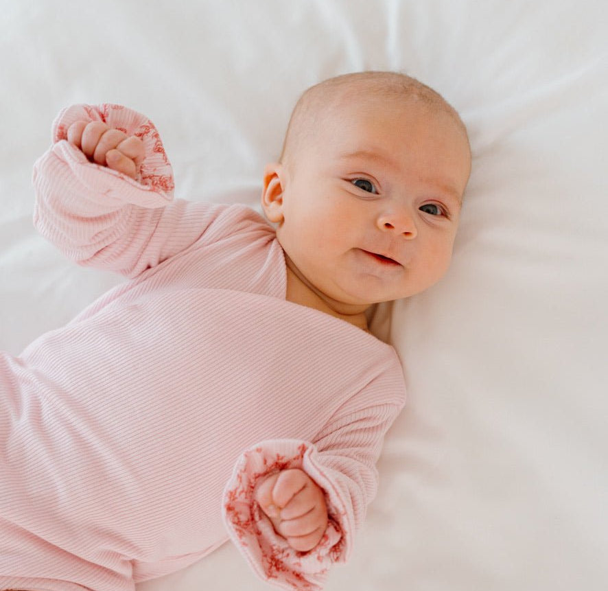 Reversible Bitty Pink Blooms design ruffle cuff long sleeved winged bodysuit in silky modal fabric.