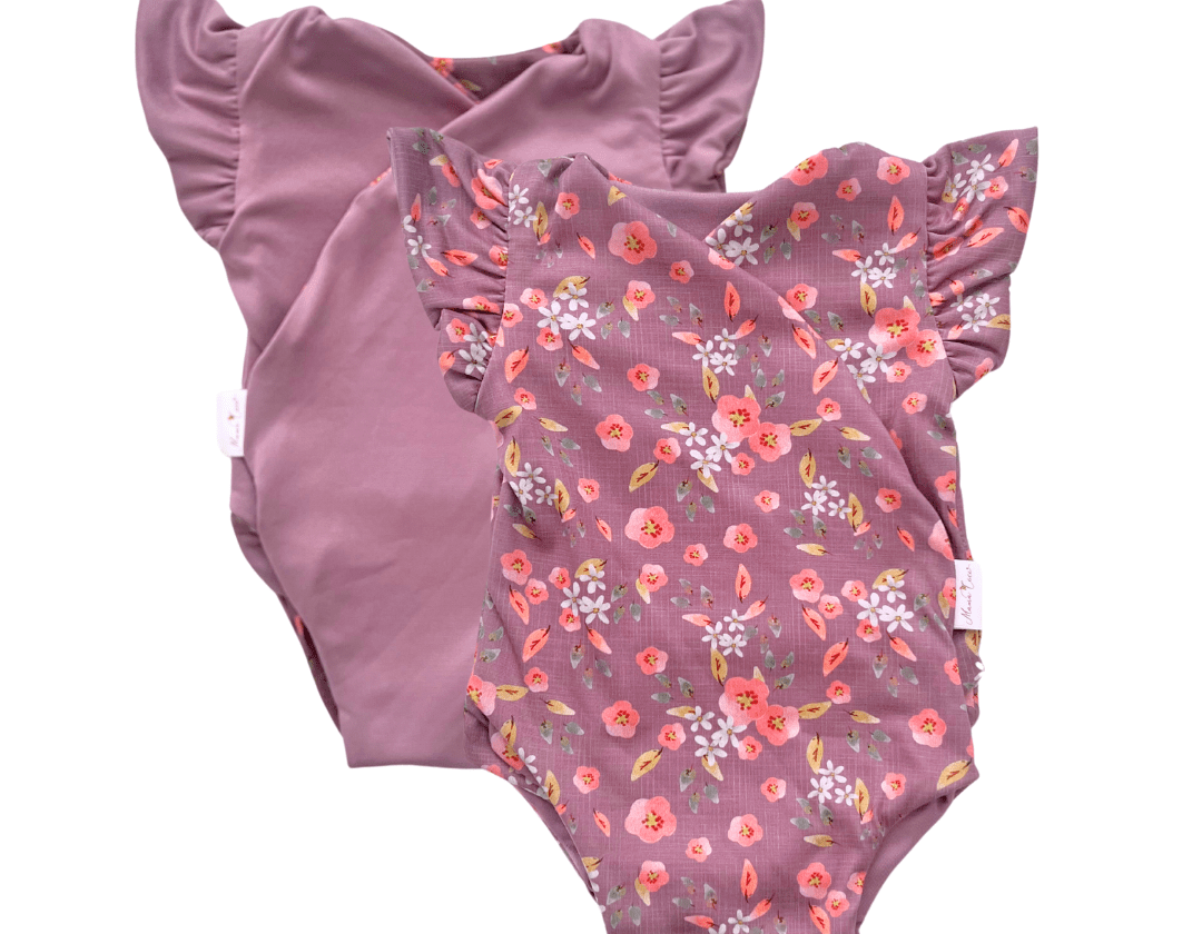 Reversible peachy lilac design flutter sleeve baby onesie in classic brushed fabric.