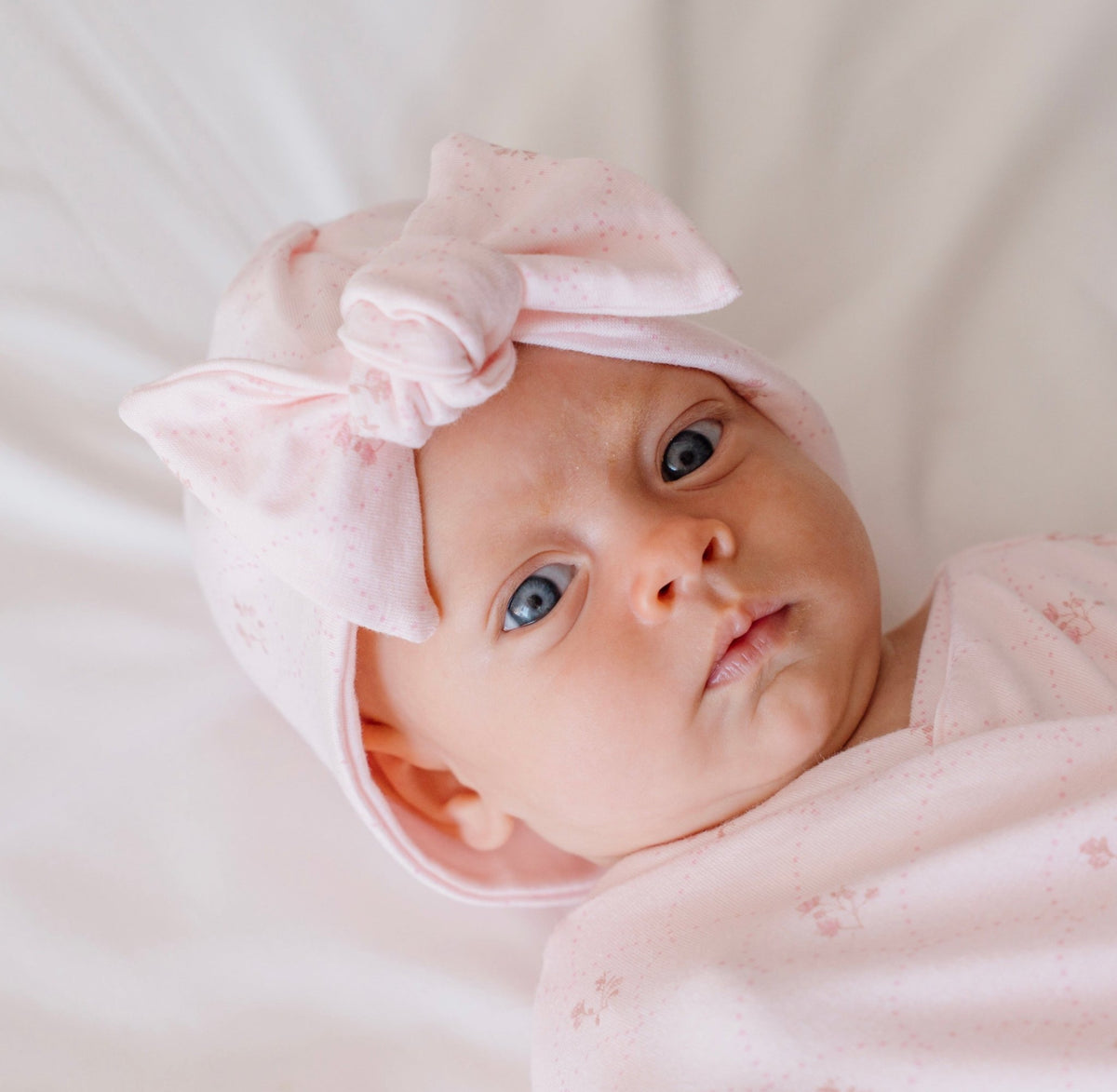 Ruched baby beanie with bow, made from bamboo cotton fabric in dainty dots design.