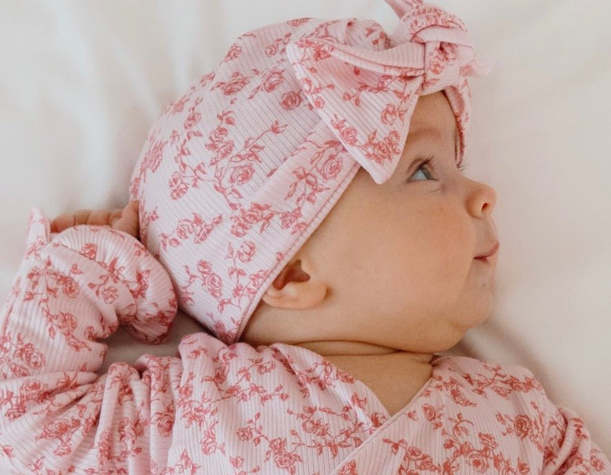 Ruched baby beanie with bow, made from silky modal fabric in bitty pink blooms design.