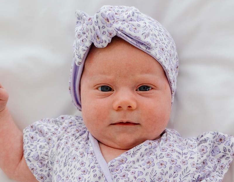 Ruched baby beanie with bow, made from silky modal fabric in purple posies design.