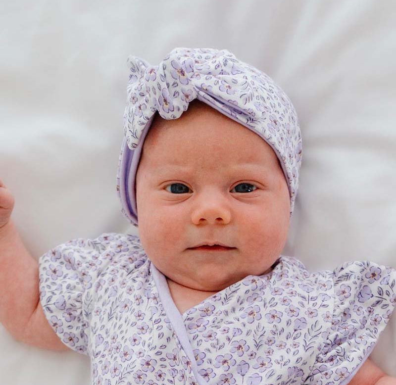 Ruched baby beanie with bow, made from silky modal fabric in purple posies design.