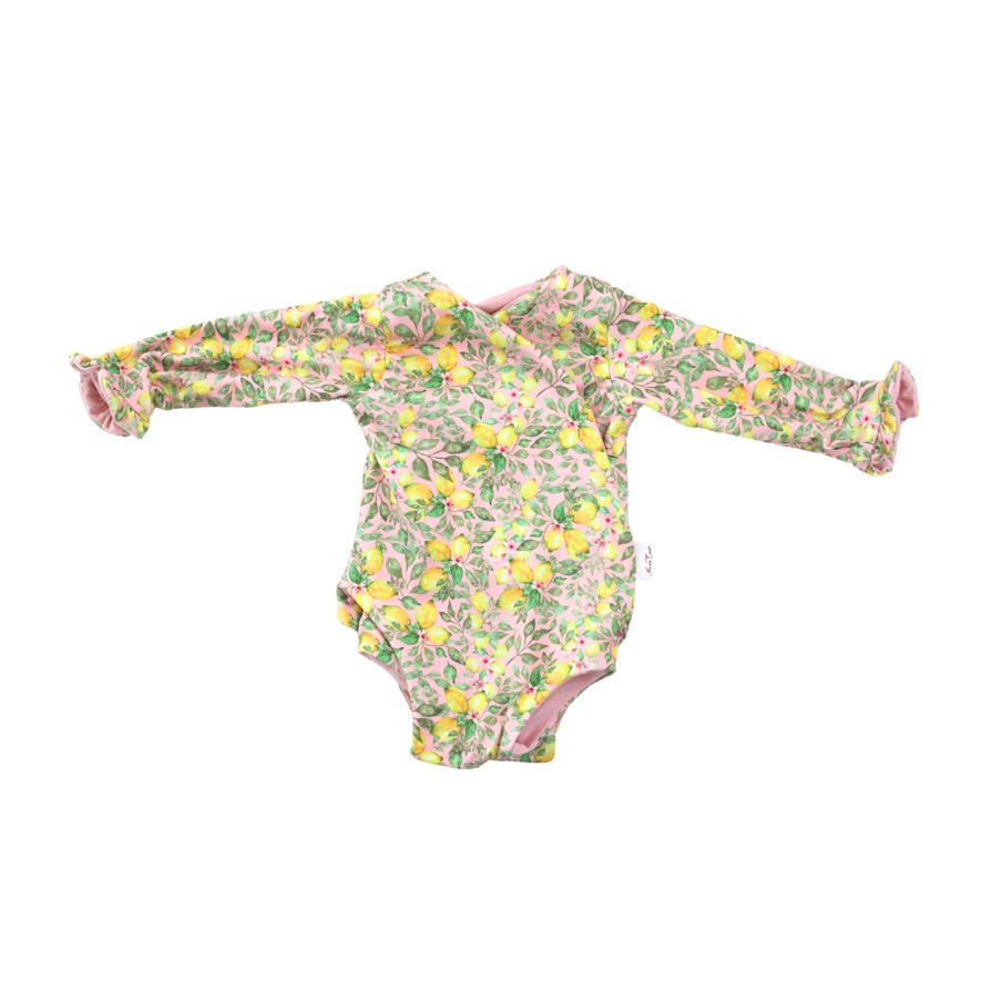 Winged long sleeve infant bodysuit crafted from cozy Pink Lemonade design brushed fabric with ruffle cuffs.