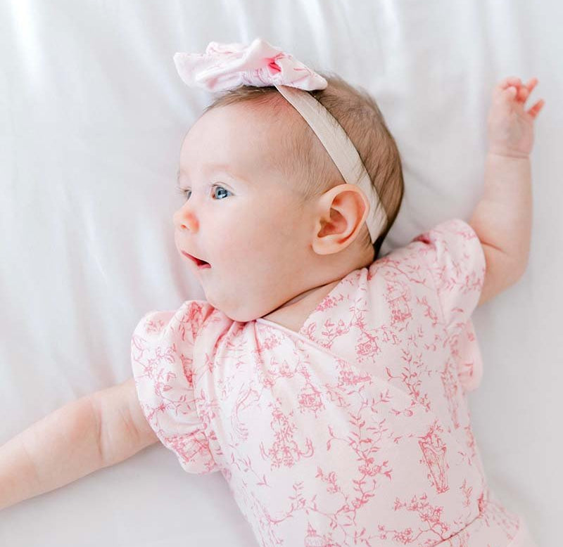 Flutter sleeve winged bodysuit for babies in whimsical garden design.