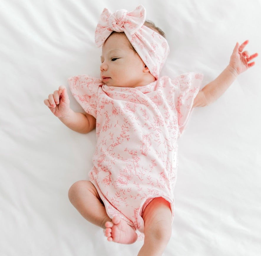 Whimsical garden design flutter sleeve baby onesie in bamboo cotton fabric.