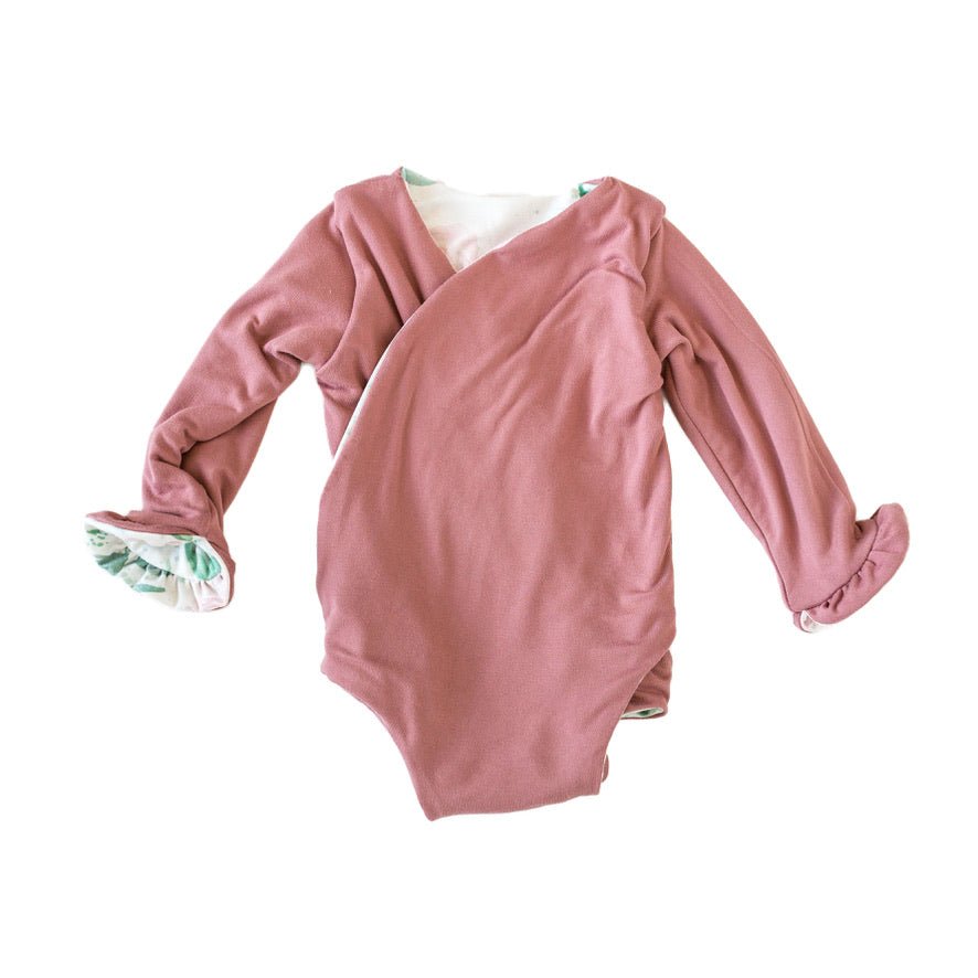 Winged long sleeve infant bodysuit crafted from cozy Blushing Eucalyptus design brushed fabric with ruffle cuffs.

