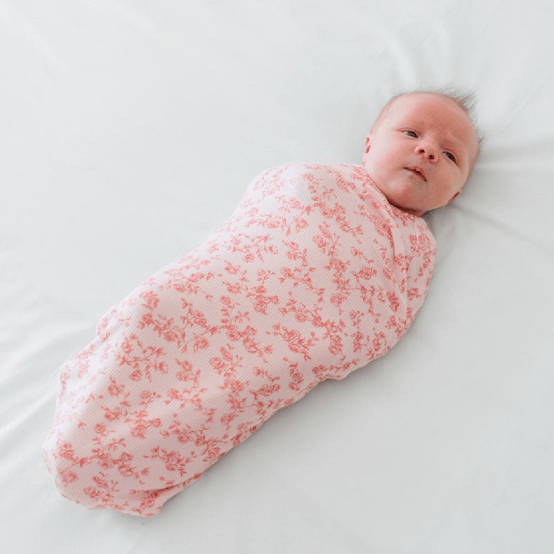 Bitty Pink Blooms pattern showcased on a Cocoon swaddle baby blanket in Silky Modal fabric styles.