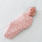 Bitty Pink Blooms pattern showcased on a Cocoon swaddle baby blanket in Silky Modal fabric styles.