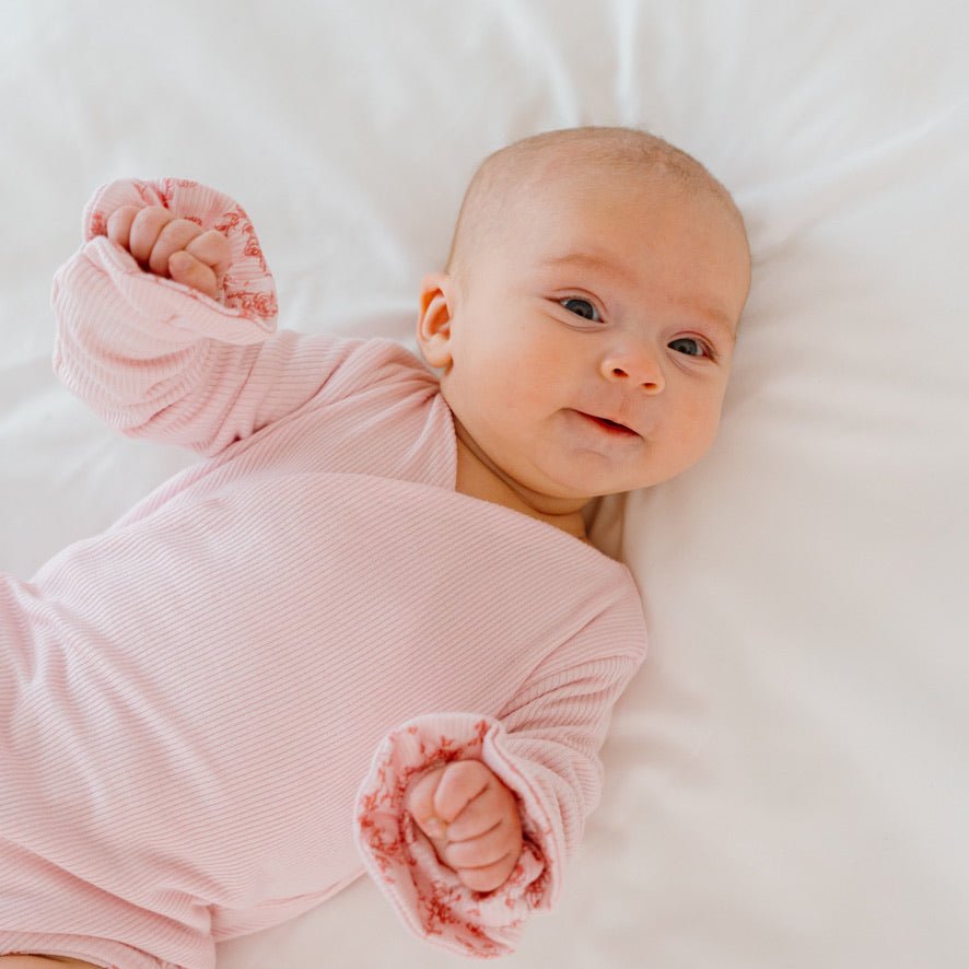 Reversible Bitty Pink Blooms design ruffle cuff long sleeved winged bodysuit in silky modal fabric.