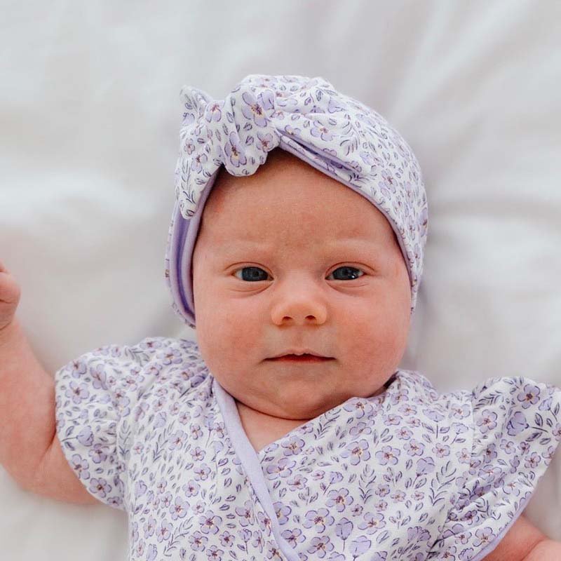 Ruched baby beanie with bow, made from silky modal fabric in purple posies design.