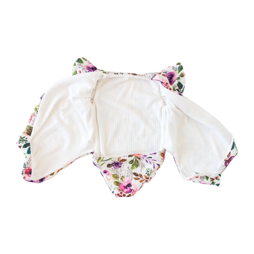 Reversible boutique baby bodysuit in Ivory Wildflowers print and Classic Brushed fabric styles.